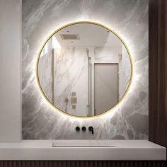 a bathroom with a round mirror above the sink and marble counter tops on the wall