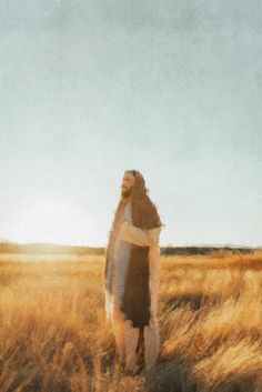 a woman standing in the middle of a field with her arms wrapped around her body