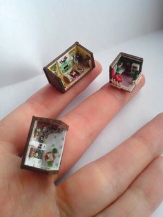 three miniature houses sitting on top of each other in someone's hand with their fingers