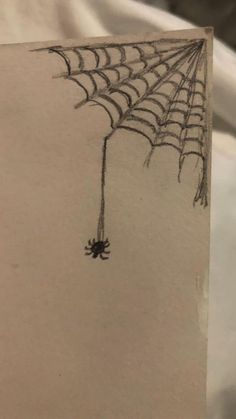 a drawing of a spider web hanging upside down on a sheet of paper with the image of a spiderweb attached to it