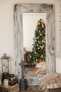 a mirror sitting on top of a table next to a christmas tree in a living room