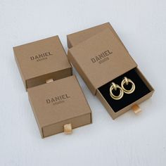 two boxes with gold rings in them sitting on a white surface next to each other