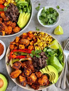 two bowls filled with meat, vegetables and avocado on top of a table