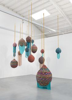 an art installation with balls and chains hanging from it's sides in a white room