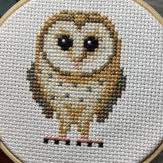 an owl cross stitched onto a white piece of cloth