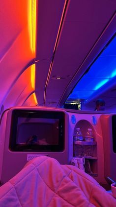 the inside of an airplane with colorful lights on it's ceiling and bedding