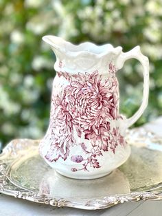 a pink and white pitcher sitting on top of a glass plate