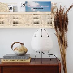 a table with some books and a vase on top of it next to a lamp