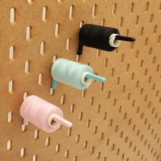 three different colored spools on a pegboard