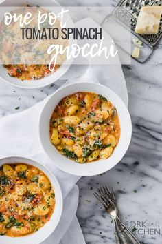 three white bowls filled with pasta and cheese on top of a marble table next to silverware