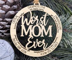 a wooden ornament with the words worst mom ever on it and pine cones