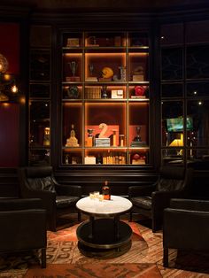 a living room with leather chairs and a table in front of a book shelf filled with books