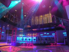 an empty dance floor is lit up with bright colored lights and spotlights in the background