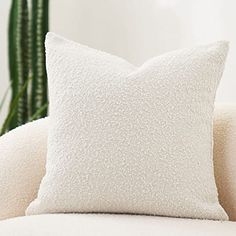 a white pillow sitting on top of a couch next to a potted green plant