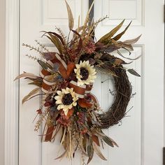 a wreath with dried flowers and leaves hanging on the front door to give it an autumn feel