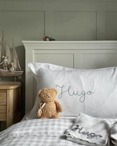 a teddy bear sitting on top of a bed next to pillows and pillowcases