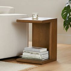 a small table with books on it next to a white chair and potted plant