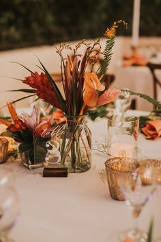 the table is set with vases and candles for an elegant wedding reception or special event