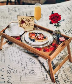 a tray with breakfast food on it sitting on a bed