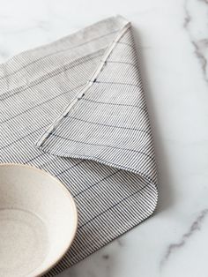 a white bowl sitting on top of a table next to a folded piece of cloth