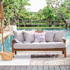 a couch sitting on top of a wooden floor next to a swimming pool with trees in the background