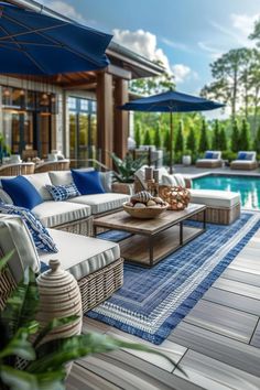 an outdoor living area with blue and white furniture next to a pool in the background