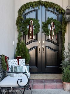 the front door is decorated for christmas with wreaths and bells