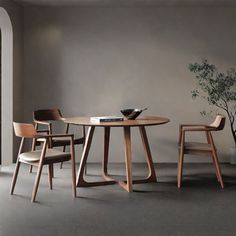 three chairs and a table in an empty room with a potted plant on the floor