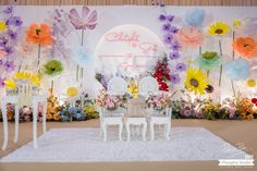 a table and chairs are set up in front of a flower wall with flowers on it