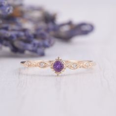 a close up of a ring on a table with lavender flowers in the back ground