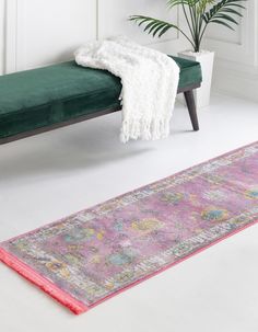 a green bench sitting next to a pink rug on top of a white floor in front of a plant