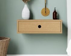 a white vase sitting on top of a wooden shelf next to a wall mounted clock