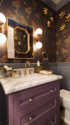 a bathroom with purple cabinets and gold accents on the wall, along with a white toilet