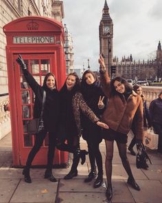 four girls posing in front of a red phone booth with big ben in the background