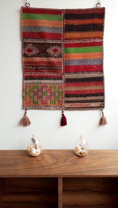 two wall hangings on the side of a wooden shelf with shells and seashells