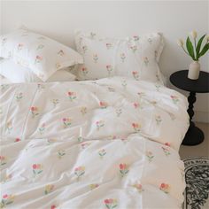 an unmade bed with white sheets and flowers on it