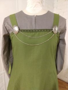 a woman's green dress with silver buttons on the back