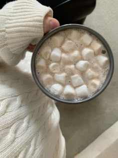 someone holding a cup of hot chocolate with marshmallows in it