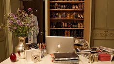 a laptop computer sitting on top of a desk next to a vase filled with flowers