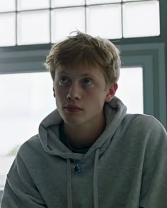 a boy in a grey hoodie looking at the camera