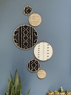 three wall hangings on the side of a blue wall next to a potted plant