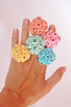 a person's hand holding five small crocheted rings in different colors and sizes