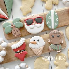 decorated cookies are on a wooden board with santa clause and snowmen in the background