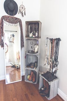 a mirror sitting on top of a wooden floor next to a shelf filled with jewelry