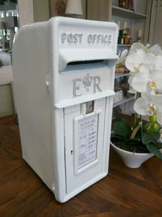 a white mailbox sitting on top of a wooden table next to a potted plant