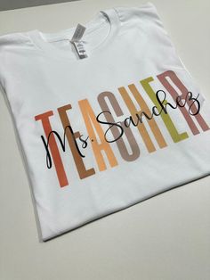 Show your appreciation for your favorite teacher with our Personalized Teacher Shirt! This custom tee makes the perfect gift for new teachers or as a thank you to your mentor. Celebrate their dedication with this unique and thoughtful Teacher Appreciation Gift. How to order 1-pick size and shirt color 2- Add to cart 3- go to cart and in the instructional box enter the custom name Example: Mrs Hernandez 4-Checkout T-shirt .unisex .eco friendly . regular size . soft & comfy Teacher Shirt With Name, Personalised T-shirt, Vinyl Teacher Shirts, Name Shirt Ideas, Dtf Shirt Ideas, Teacher T Shirt Outfits, Teacher Cricut Shirts, Tshirt Ideas For Teachers, Cricut Projects For Teachers