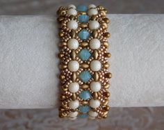 a close up of a bracelet on a person's arm with white and blue beads