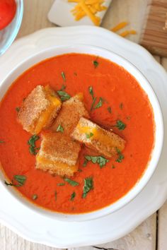 a white bowl filled with tomato soup and croutons