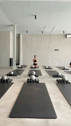 a woman sitting on top of a yoga mat in front of a group of balls