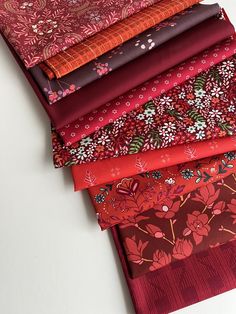 a pile of different colored fabrics sitting on top of a white table next to each other